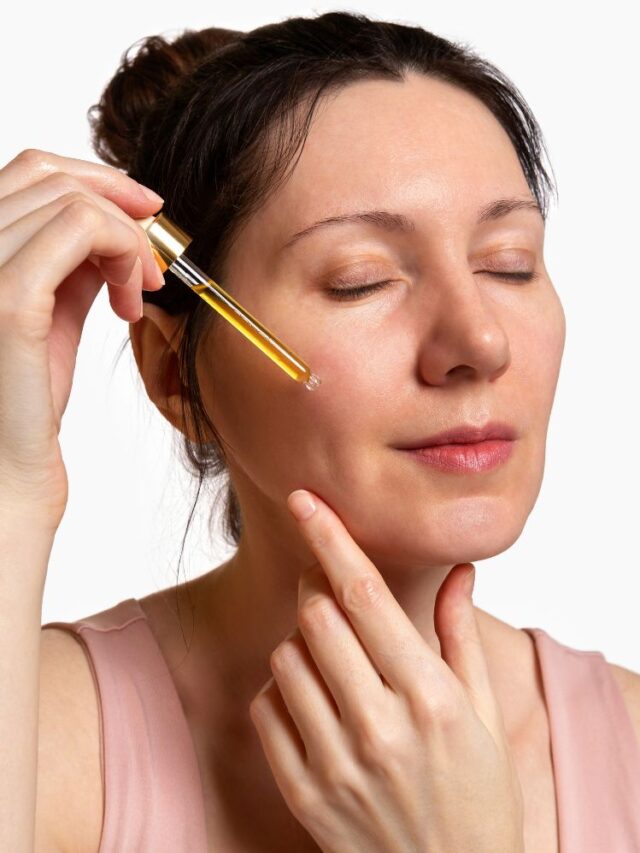 Pessoa de pele clara sem manchas aplicando sérum amarelo com conta-gotas