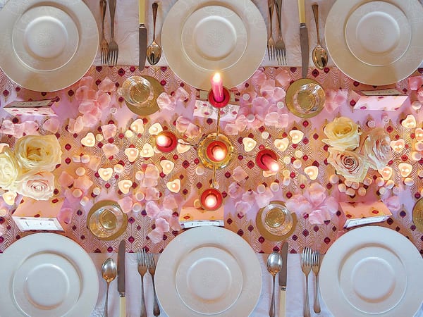 Mesa posta de Jantar romântico com luz de vela, pétalas de rosa e corações espalhados pela mesa