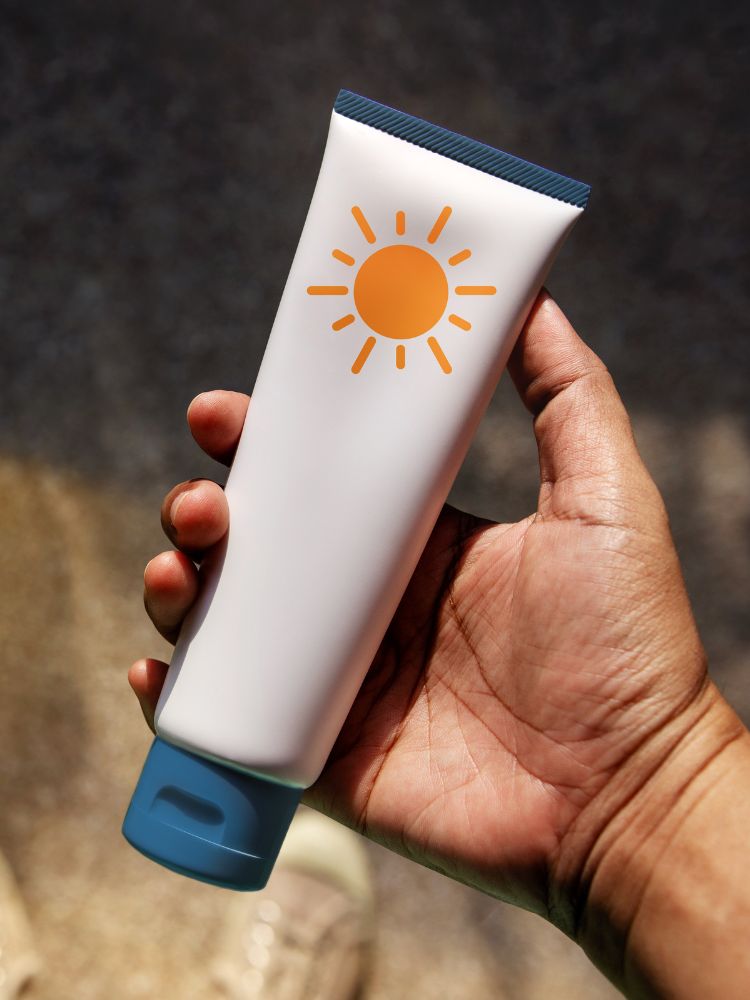 Pessoa de pele morena segurando embalagem neutra de protetor solar, de cor branca com desenho de sol amarelo