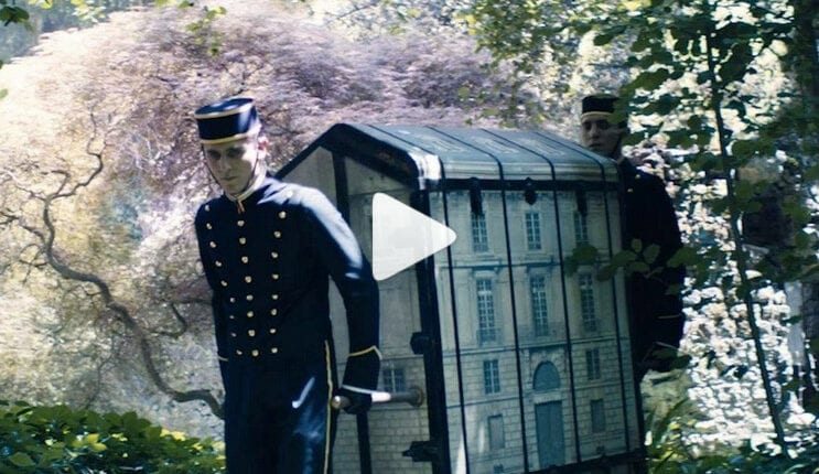 Baú de vestidos em miniatura contidos em um baú de viagem com a emblemática fachada de Paris