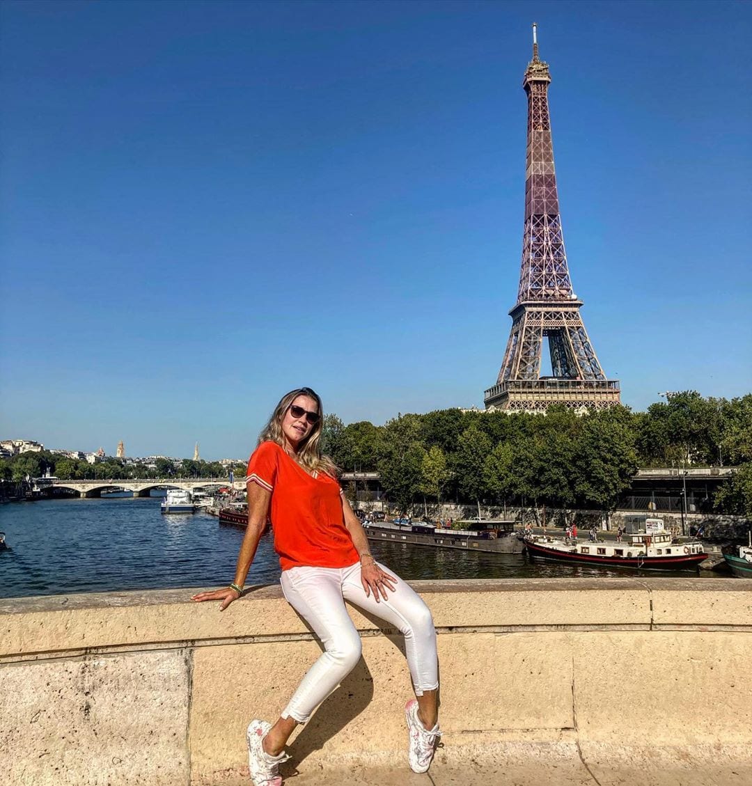 Luana sentada em pavimento de frente para torre Eiffel/Paris. 