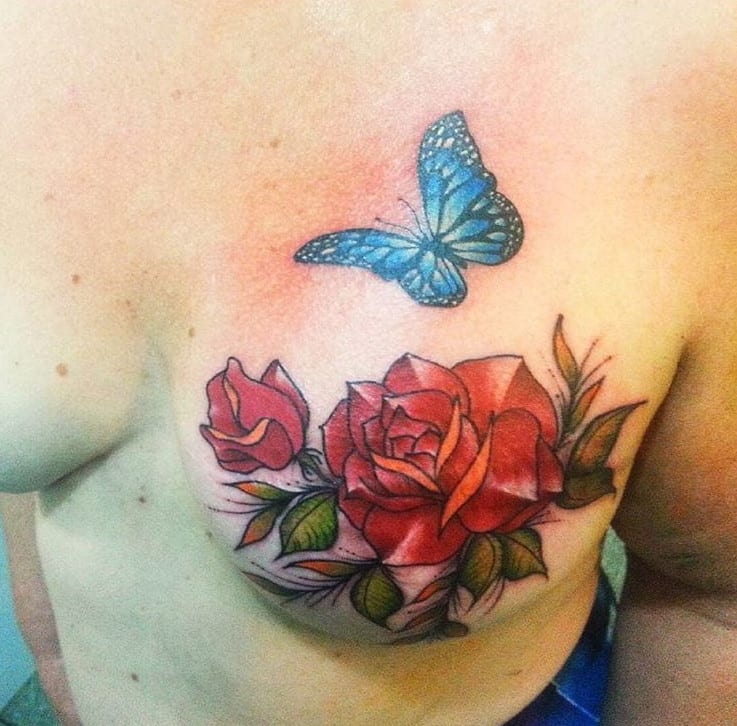 Tattoo de rosa com borboleta no lugar do bico do peito
