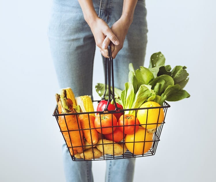 mulher carregando cesta de mercado com frutas, verduras e legumes