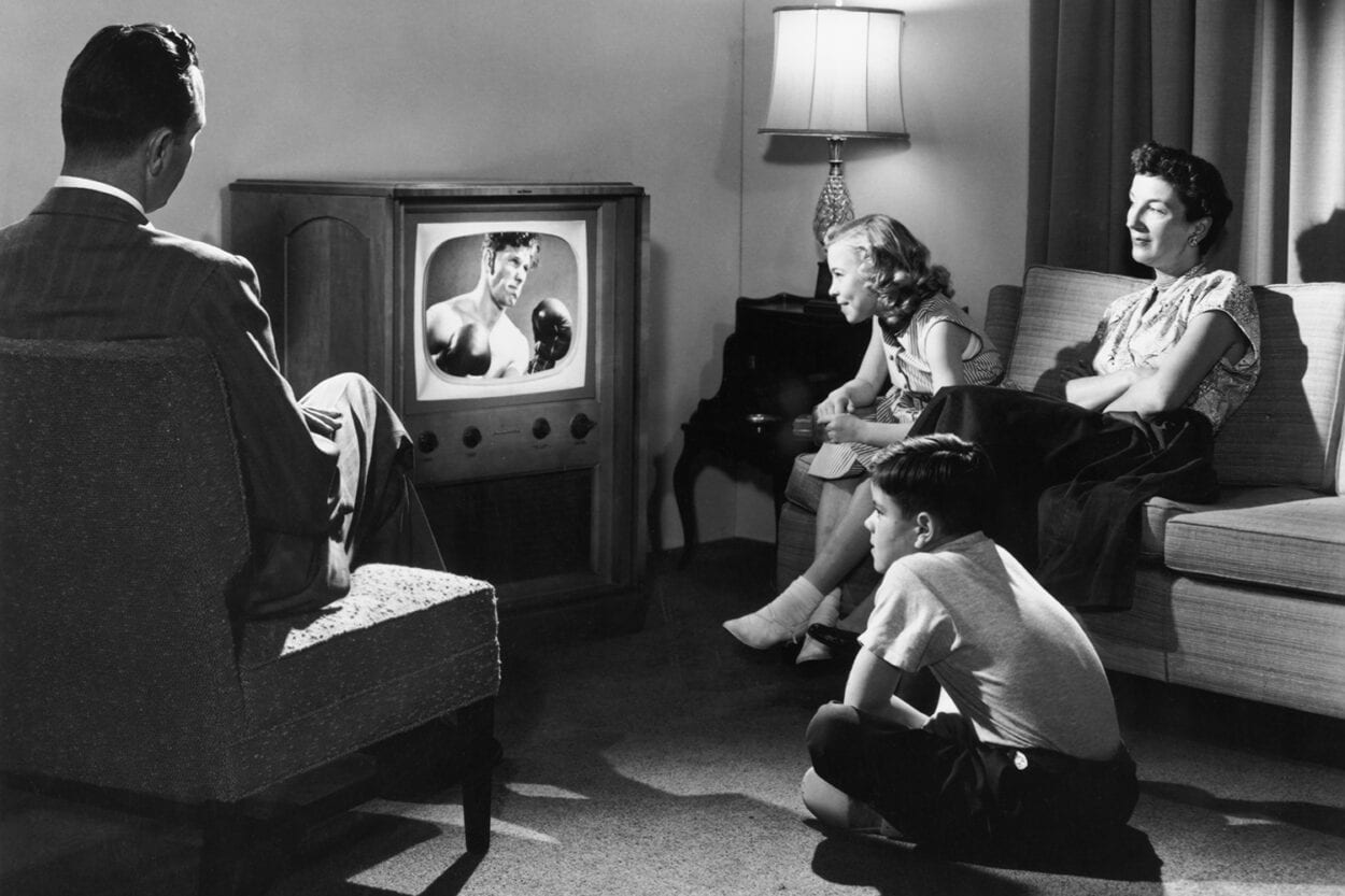 Foto antiga de família assistindo televisão.
