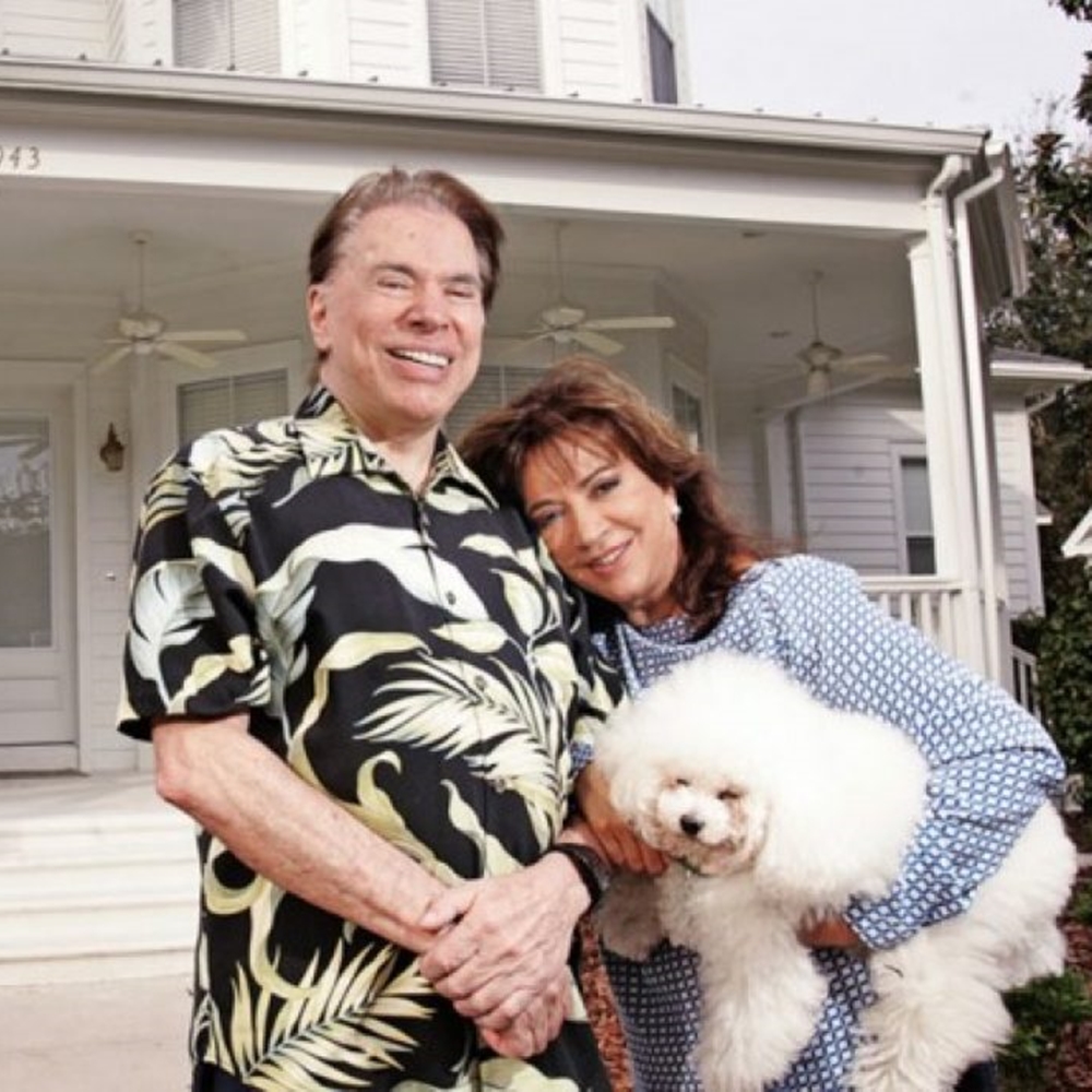 Famosos ricos, Silvio e esposa em frente a casa. 