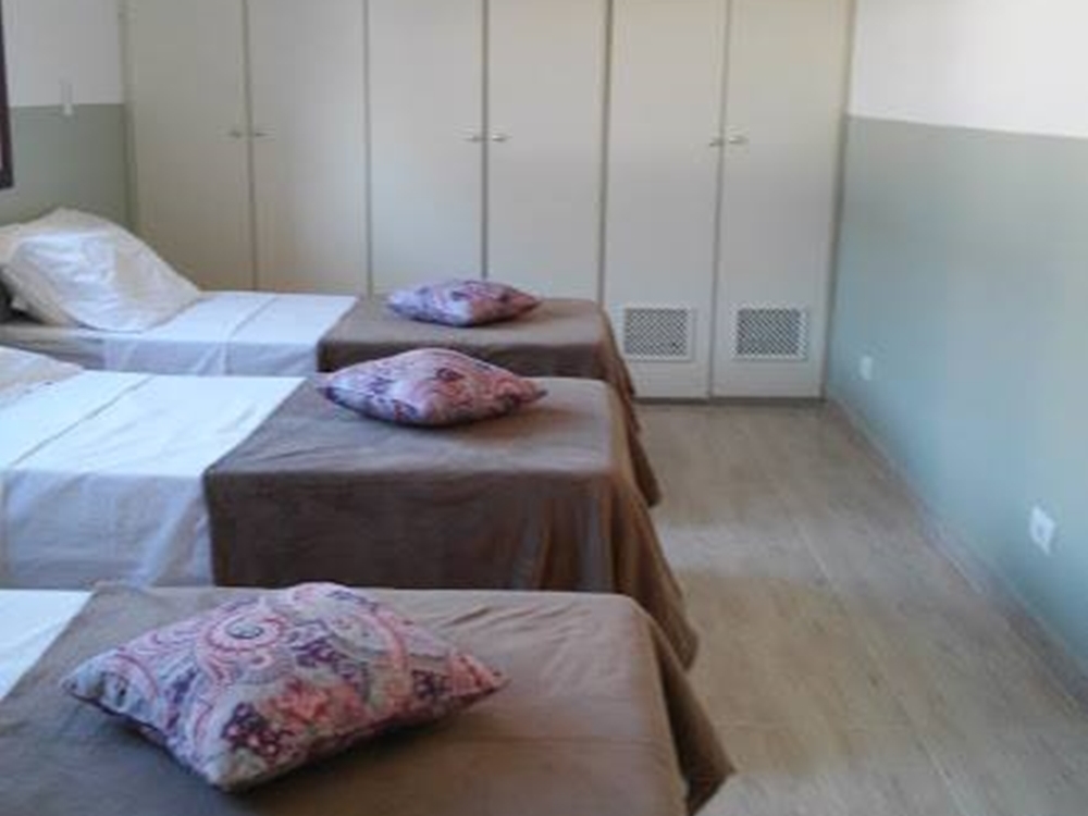 Quarto com três camas e guarda roupas. Foto de quarto com três camas.