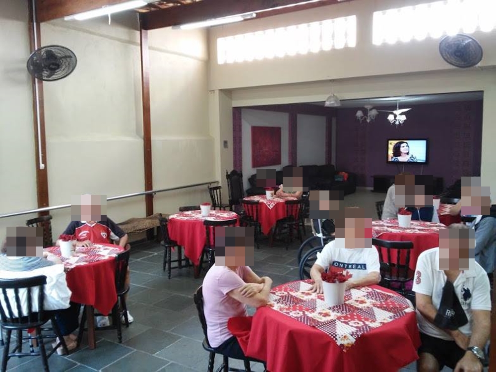 Salão de refeição com mesas de quatro cadeiras, pessoas, ventilação, televisão e mais. Salão de refeição com mesas de quatro cadeiras.