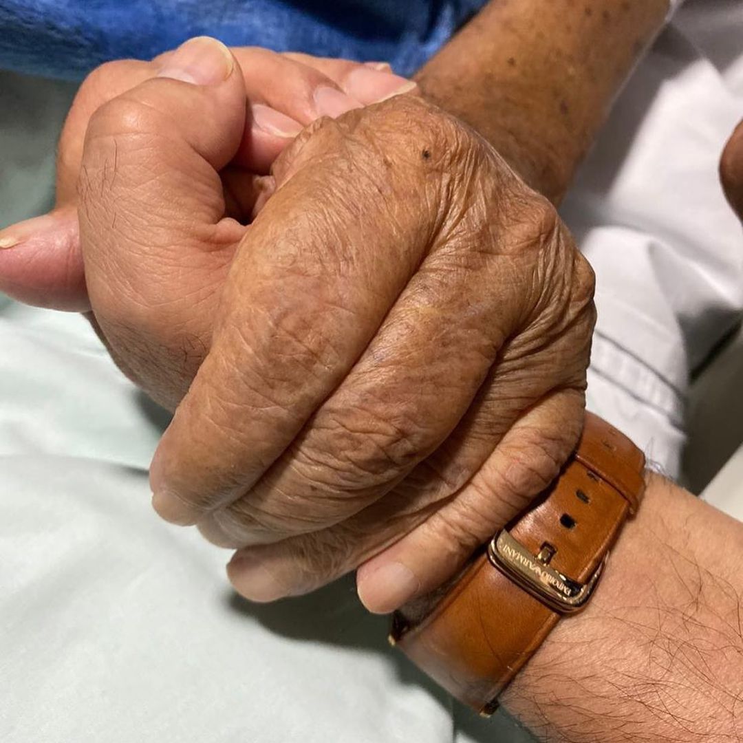 Zezé segura a mão de seu pai em hospital.