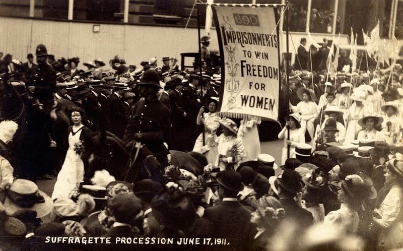 Procissão com Christabel Pankhurs, em 1911, com uma faixa onde se lê: Prisões para ganhar a liberdade para as mulheres. 