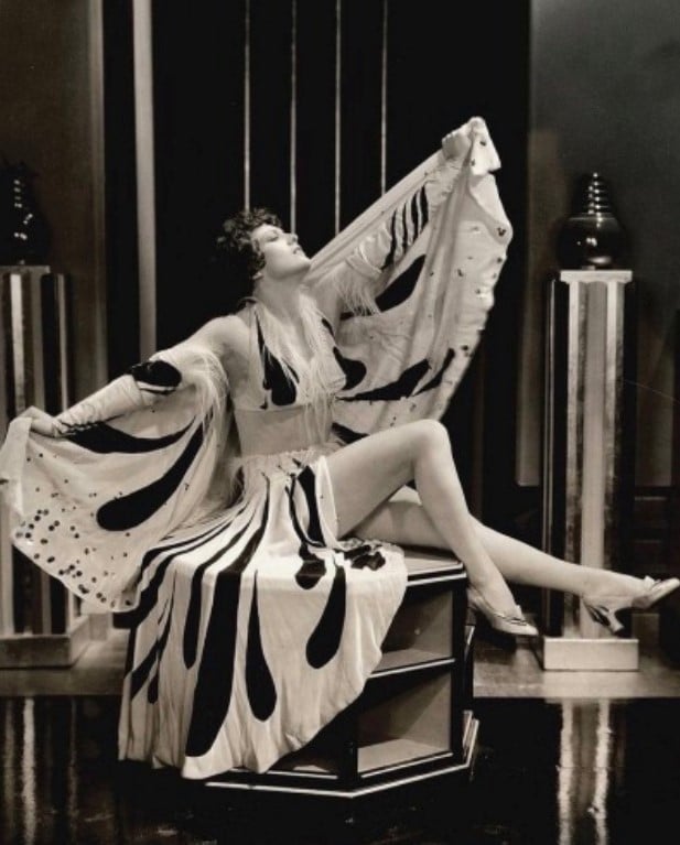 Foto da atriz Joan Crawford posando com um vestido decotado e longo, em 1932. 