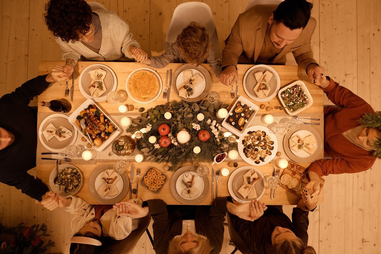 família reunida em volta da mesa rezando orações de Ano Novo