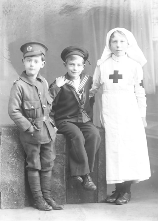 Crianças da família Dickinson vestidas com uniformes do exército, marinha e enfermeira da Primeira Guerra Mundial.