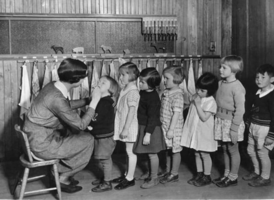 Crianças na fila para um exame de saúde em uma escola, por volta dos anos 40. 