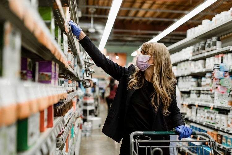 mulher de máscara fazendo compras no supermercado