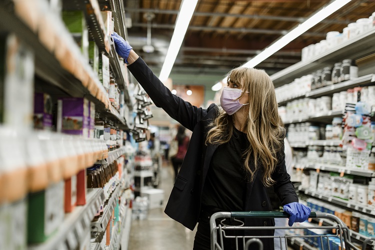 mulher de máscara fazendo compras no supermercado