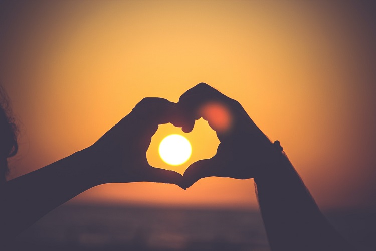 citações românticas para legendas de foto casal fazendo coração com as mãos no pôr do sol