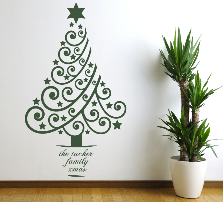 árvore natalina de adesivo na parede e frase ao lado de planta