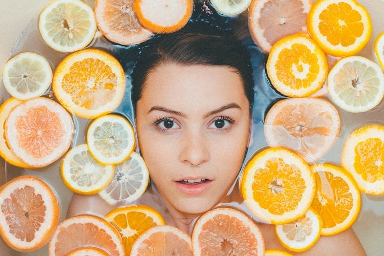 mulher mergulhada em banheira com fatias de laranja e limão