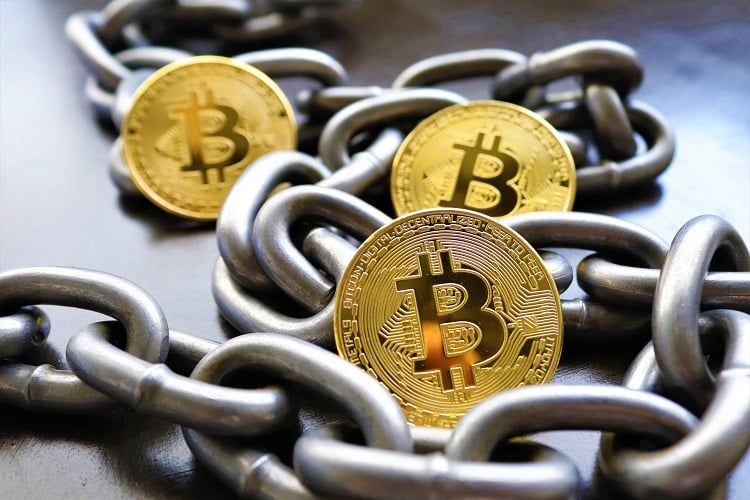 corrente enrolada em volta de moedas BitCoin