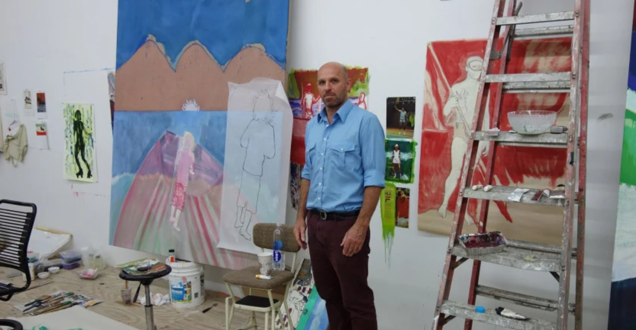 Artista Peter Doig em seu ateliê com quadros na parede