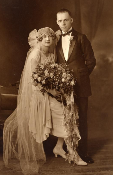 Noiva sentada e noivo em pé em foto de casamento de 1920
