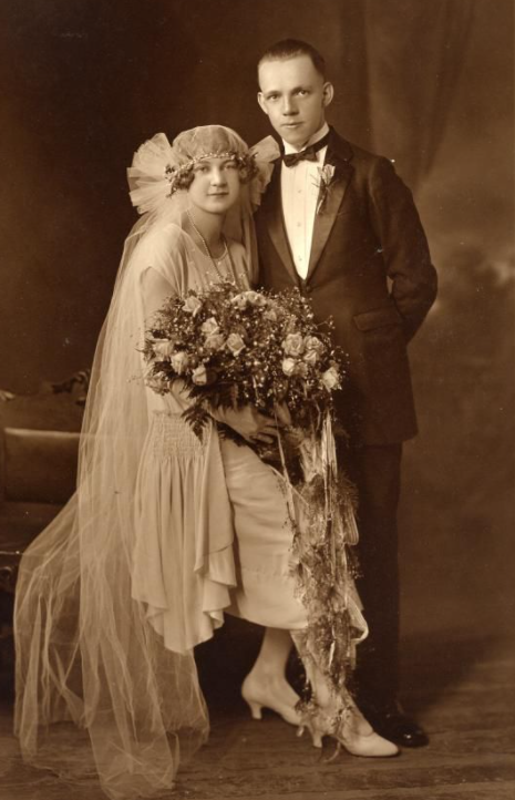Noiva sentada e noivo em pé em foto de casamento de 1920 Noiva sentada e noivo em pé em foto de casamento de 1920