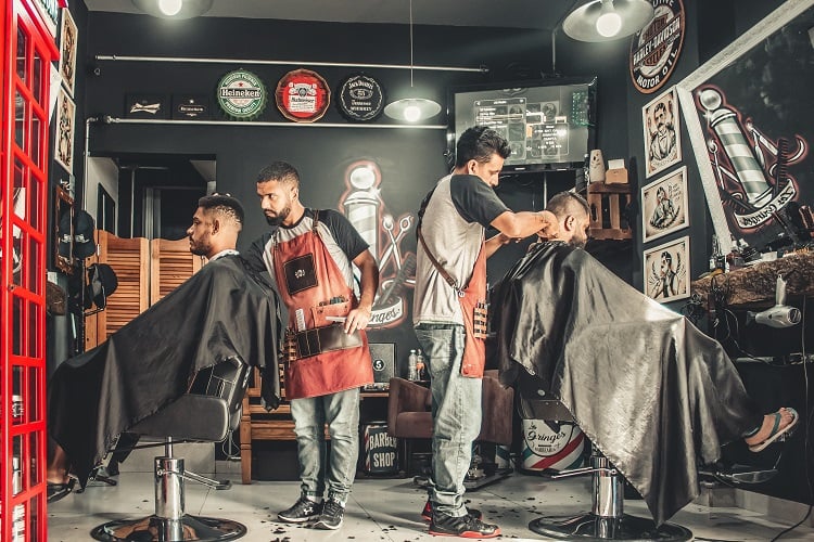 dois homens cortando o cabelo em uma barbearia