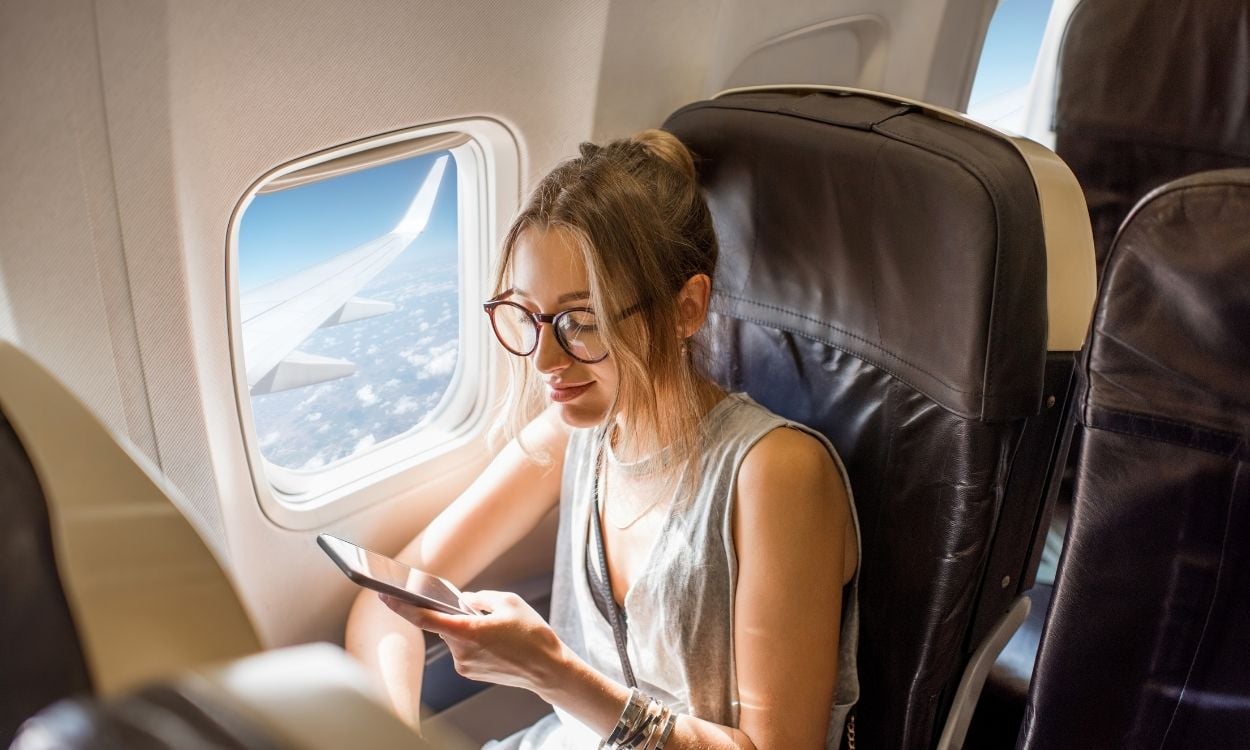 mulher no avião com celular - vender milhas