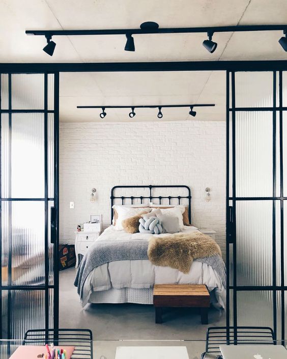 Quarto de casal estilo industrial. Porta de vidro no quarto.