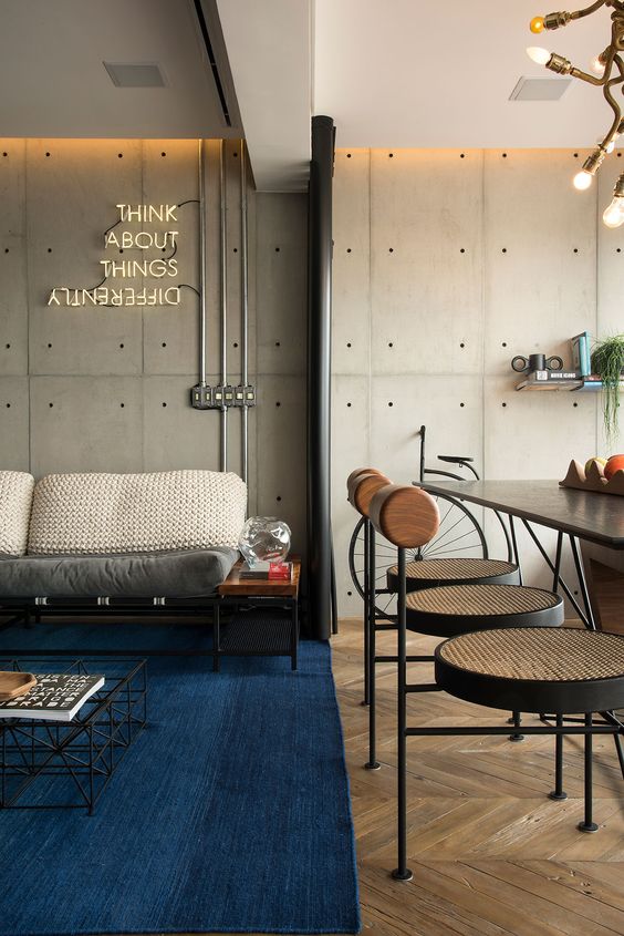 Loft com decoração industrial. Sala com tapete azul.