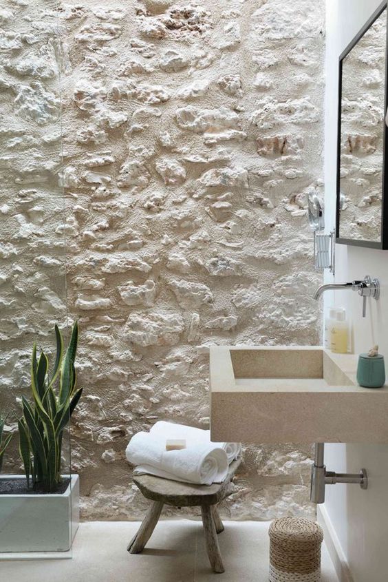 Banheiro com parede branca de pedra.
