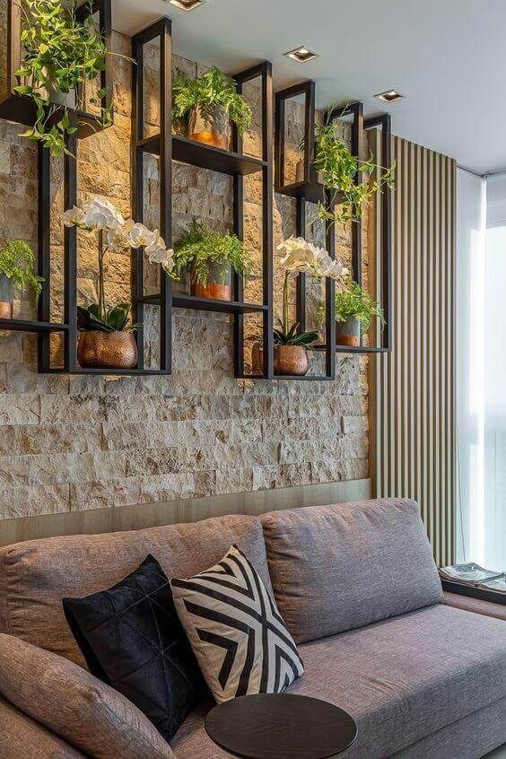 Sala com parede de pedra e plantas.