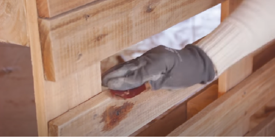 Mão com luva preta. Cuidado com pallet para lixar