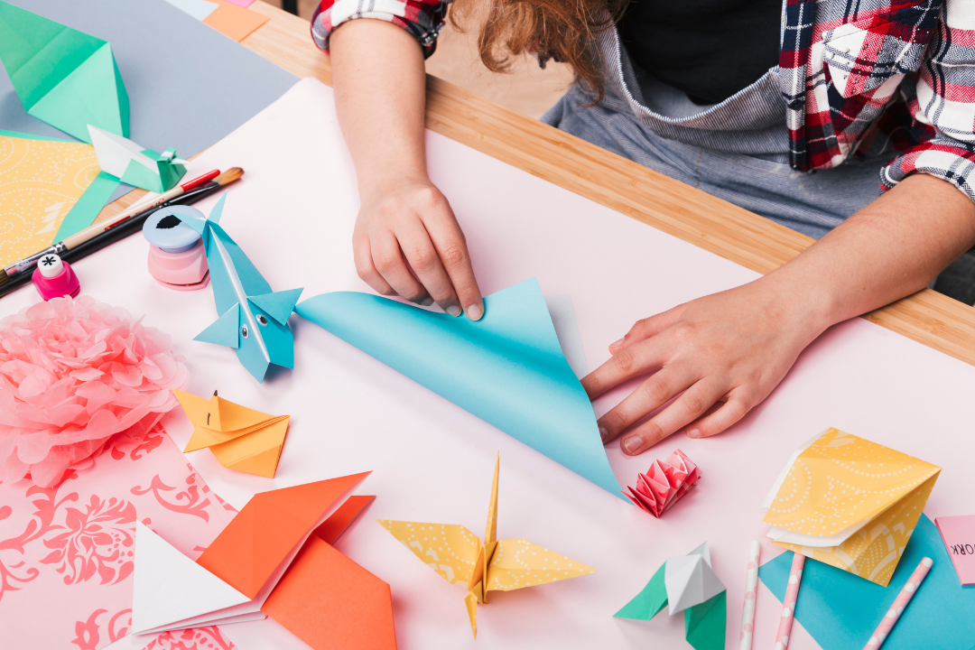 Imagem de uma artista dobrando papel de origami para fazer belas peças Imagem de uma artista dobrando papel de origami para fazer belas peças.
