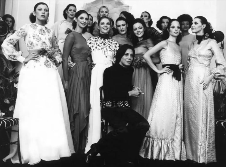 Clodovil Hernandes com modelos em um desfile de 78, com Elke Maravilha no fundo. 