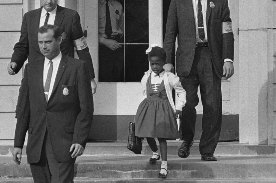 A menina Ruby Bridges, de 6 anos, a ser escoltada em New Orleans em 1960 diante do protesto de pais e outros cidadão (ela foi a primeira criança negra a entrar em um escola de brancos nessa região). 