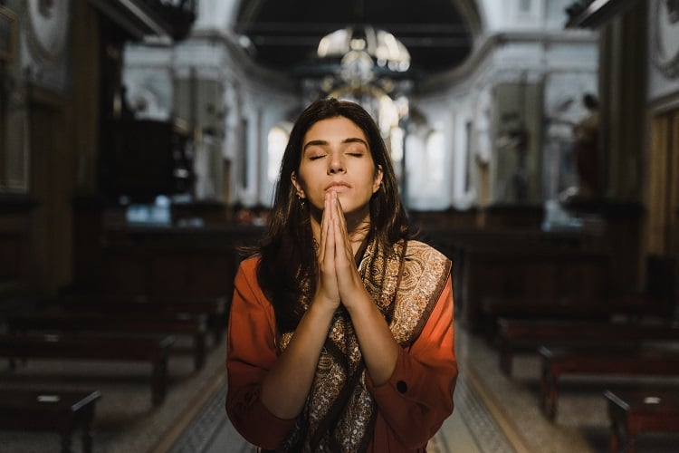 mulher rezando de olhos fechados