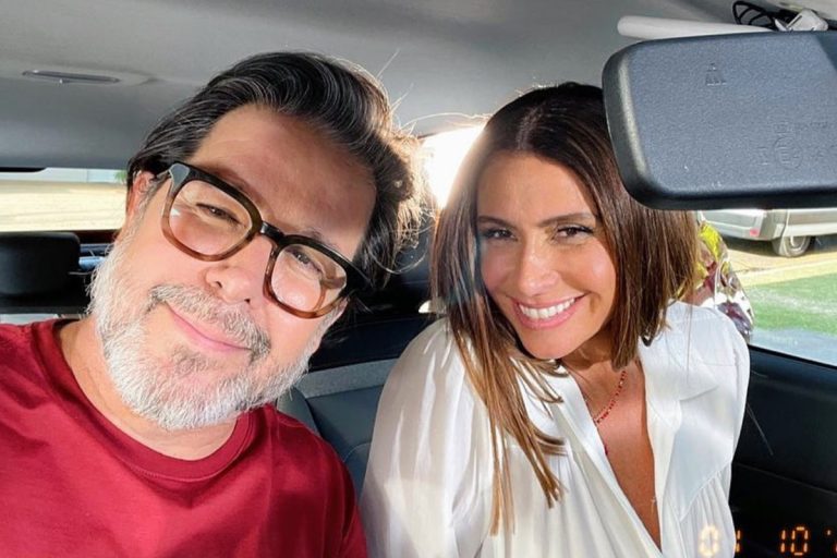 A imagem mostra um homem de barba grisalha, óculos e camisa vermelha sorrindo ao lado de uma mulher de cabelos castanhos, vestindo uma blusa branca, também sorrindo. Ambos estão dentro de um carro, iluminados pela luz do sol. Ele é Murilo Benício e ela Giovanna Antonella, um dos casais de famosos com filhos que se separaram.
