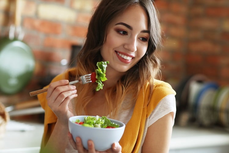 mulher comendo tigela de salada