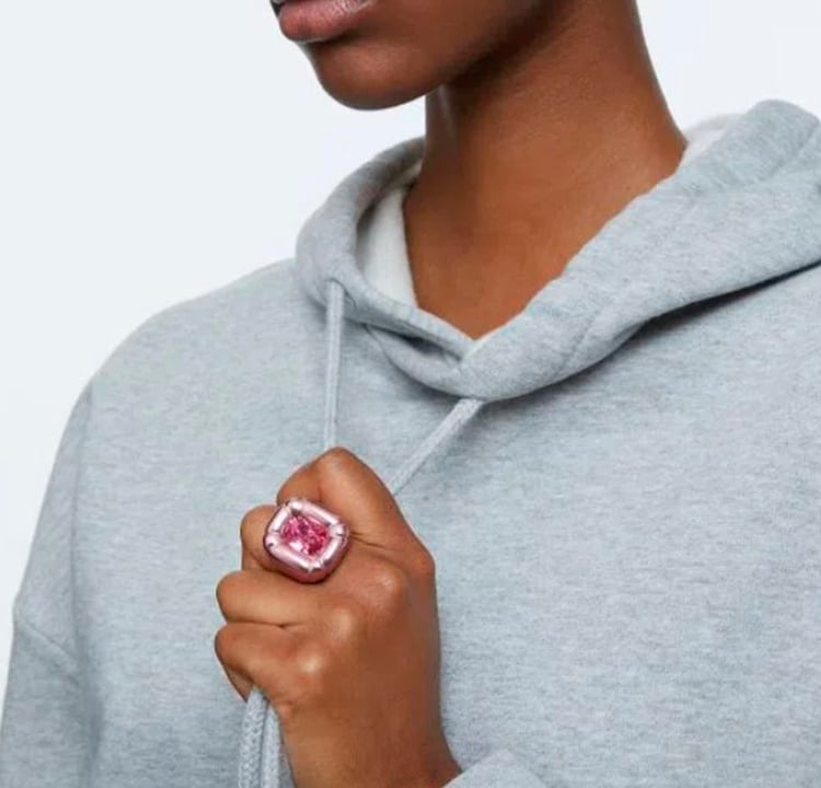 Foto de uma modelo usando um anel grande e rosa na mão direita.