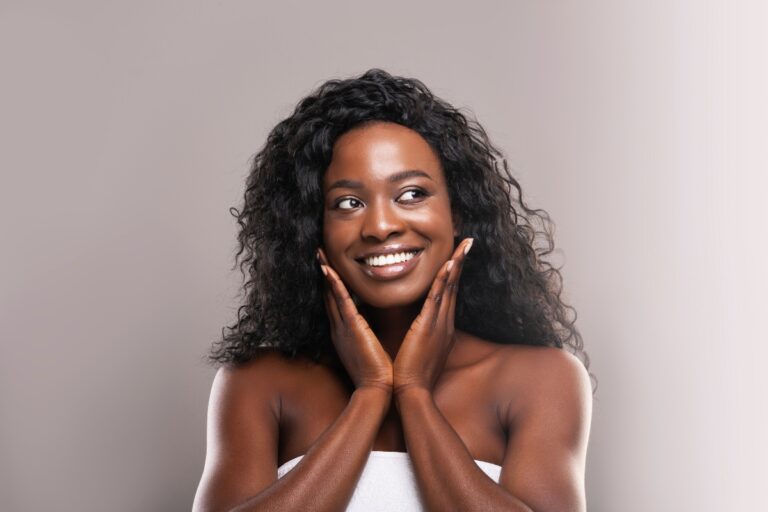 Mulher negra enrolada na toalha, com pele linda e sem rugas e sorriso