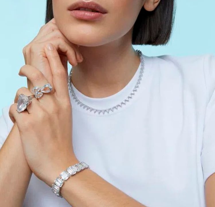 Foto de uma mulher usando dois aneis e uma pulseira de cristais brancos.