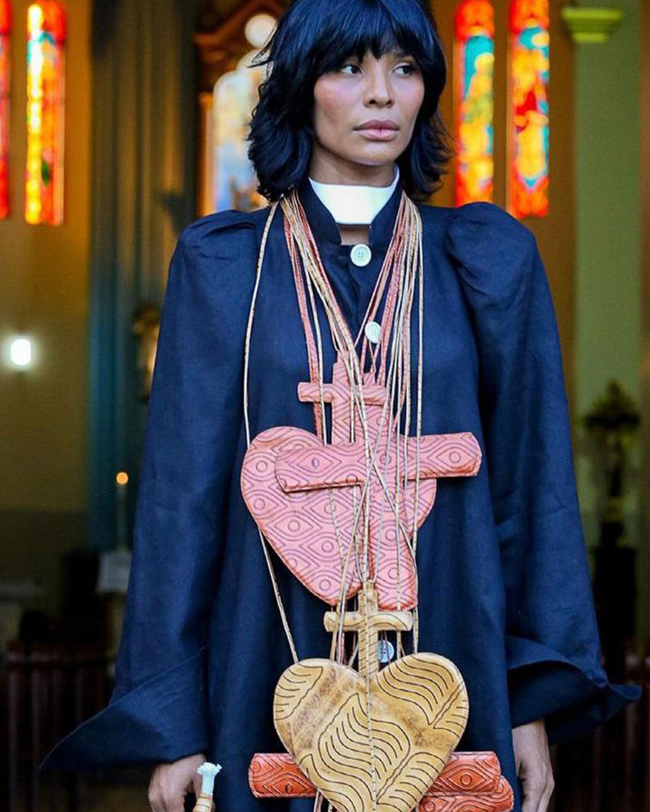 A modelo Suyane Moreira com uma jaqueta azul marinho e colares grandes em formato de coração.