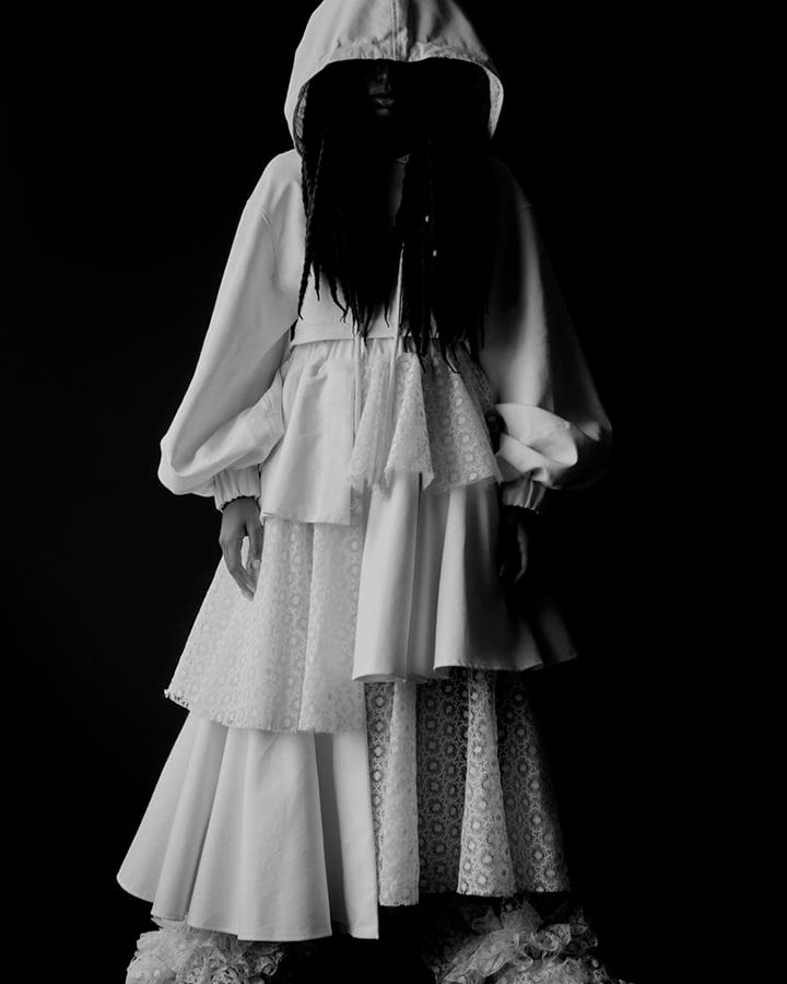 Vestido branco com capuz. Foto em preto e branco.