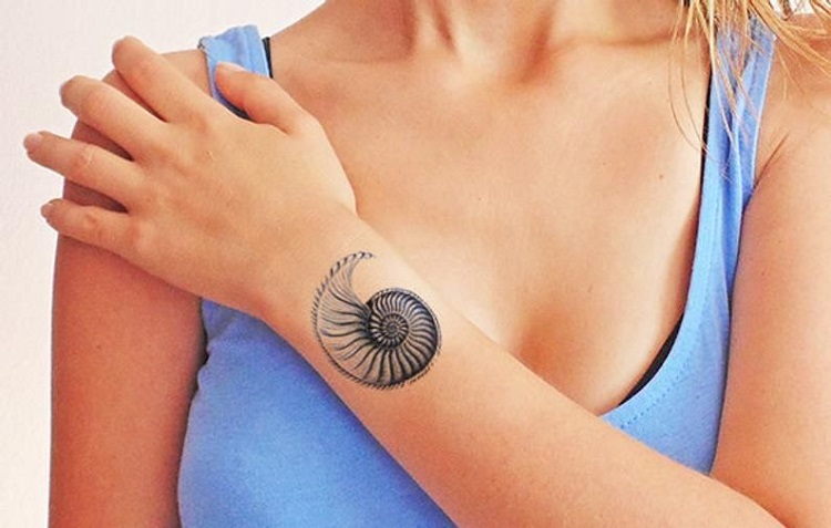 mulher com tatuagem de concha no braço