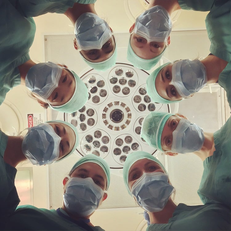 médicos em círculo usando máscara e olhando para baixo