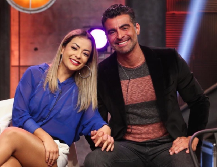 Li e JP sentados, de mãos dadas, olhando para a câmera, terceiro lugar do Power Couple Li e JP sentados, de mãos dadas, olhando para a câmera