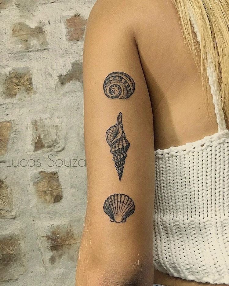 mulher com tatuagens de concha no braço