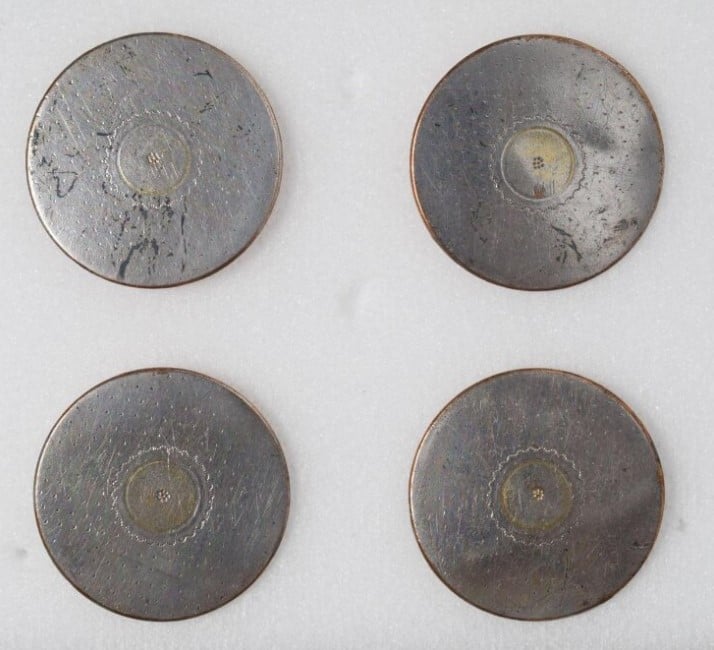 Foto de 4 botões feito em metal liso e achatado com estampa floral no centro sobre fundo branco