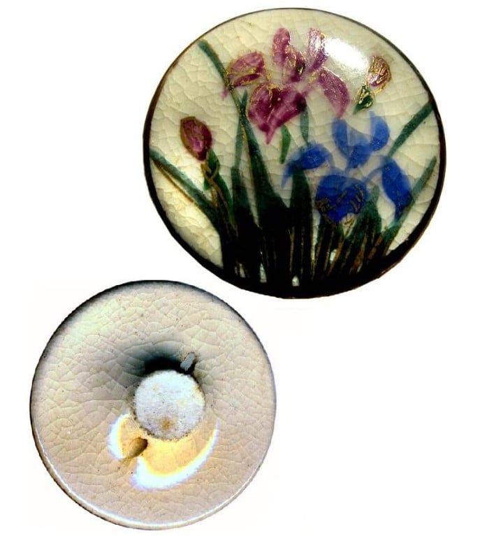 Foto de um botão de roupa feito de porcelana japonesa branca decorado com flores vermelhas e azuis